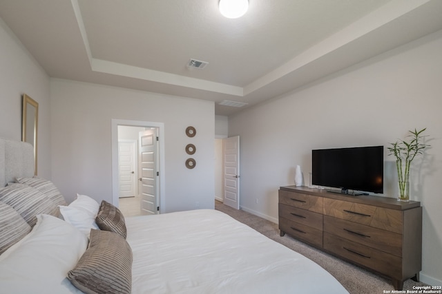 bedroom featuring light colored carpet and a tray ceiling