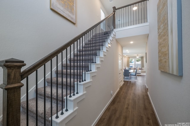 stairs featuring a high ceiling and dark hardwood / wood-style flooring