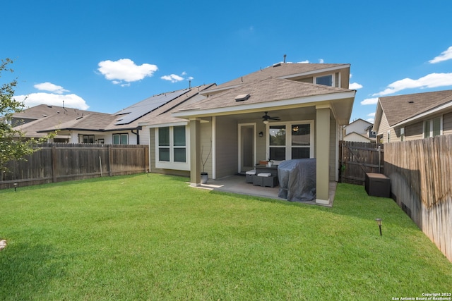 rear view of property featuring a lawn, a patio, solar panels, and ceiling fan