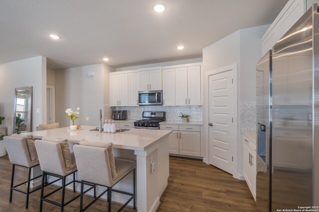 kitchen with stainless steel appliances, dark wood-type flooring, a kitchen breakfast bar, and white cabinetry