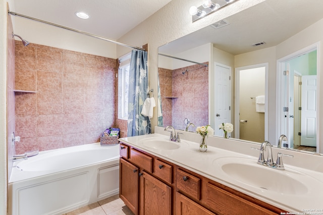 bathroom with a textured ceiling, dual bowl vanity, a bath to relax in, and tile flooring