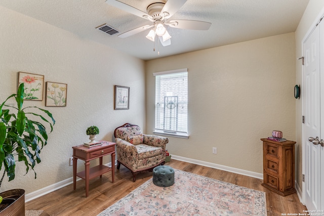 sitting room with a textured ceiling, light hardwood / wood-style floors, and ceiling fan