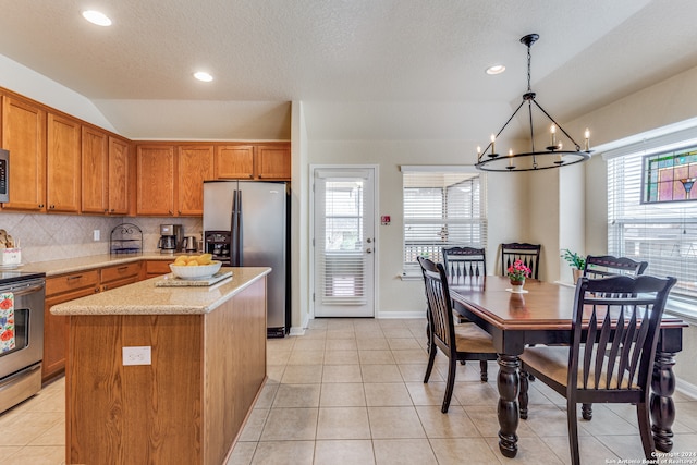 kitchen with a chandelier, light tile floors, a center island, backsplash, and hanging light fixtures