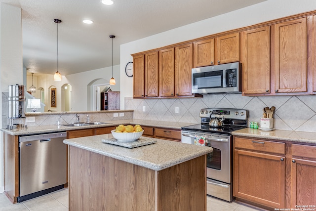 kitchen with pendant lighting, stainless steel appliances, backsplash, light tile floors, and sink