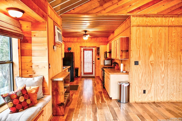 kitchen featuring wooden ceiling, wood walls, black refrigerator, and light hardwood / wood-style floors