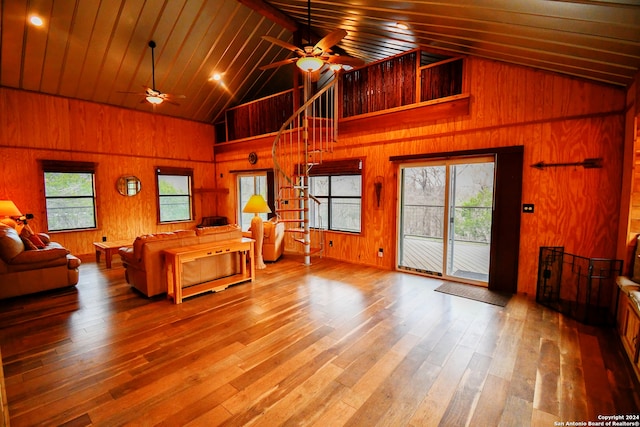 living room with high vaulted ceiling, hardwood / wood-style flooring, and wooden walls