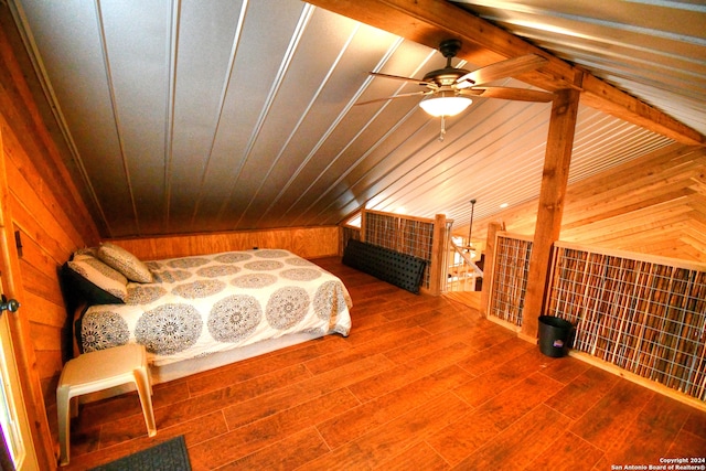 bedroom featuring ceiling fan, wood walls, vaulted ceiling with beams, and hardwood / wood-style flooring