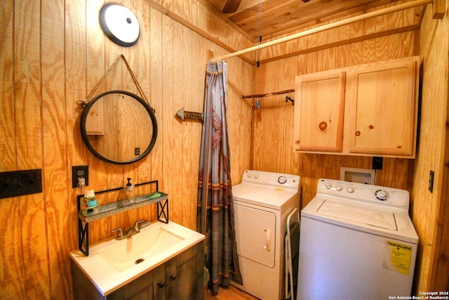 laundry room with cabinets, washer and clothes dryer, wooden walls, sink, and wooden ceiling