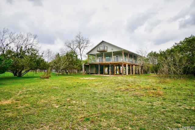 rear view of house with a lawn and a balcony