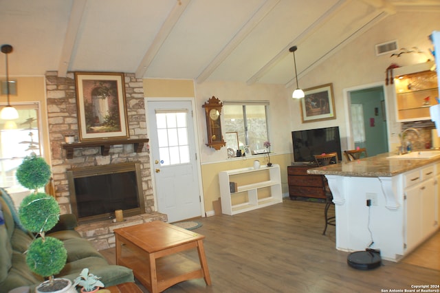 interior space featuring a stone fireplace, sink, vaulted ceiling with beams, and dark hardwood / wood-style floors