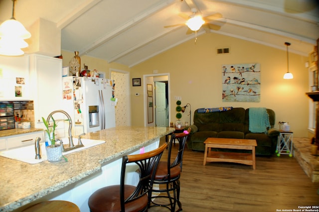 kitchen with pendant lighting, a breakfast bar area, white cabinets, refrigerator with ice dispenser, and light stone counters