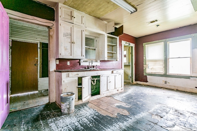 kitchen featuring wooden ceiling, white cabinetry, and sink