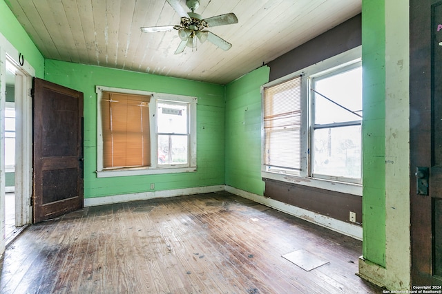 empty room featuring wood walls, ceiling fan, dark wood-type flooring, and wood ceiling