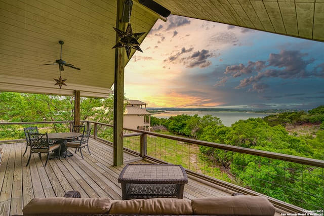 deck at dusk featuring a water view