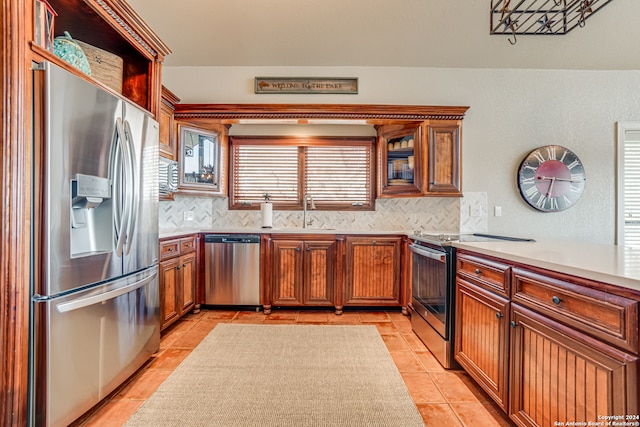 kitchen with backsplash, sink, light tile flooring, and stainless steel appliances