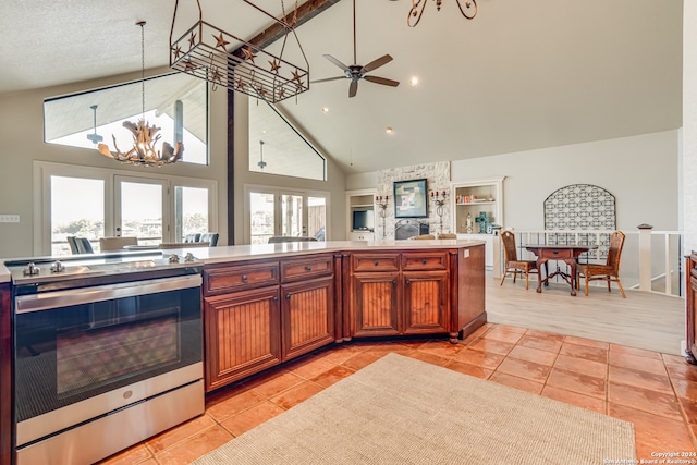 kitchen featuring stove, high vaulted ceiling, plenty of natural light, and ceiling fan with notable chandelier