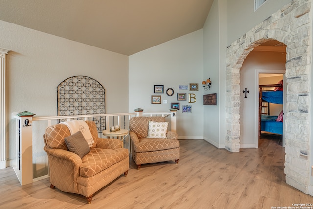 living area with high vaulted ceiling and light hardwood / wood-style flooring