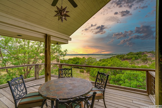 deck at dusk featuring ceiling fan