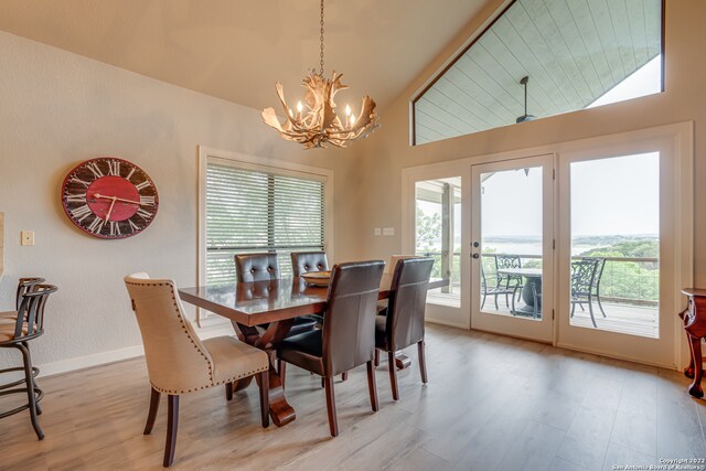 dining space featuring a chandelier, high vaulted ceiling, and light hardwood / wood-style floors