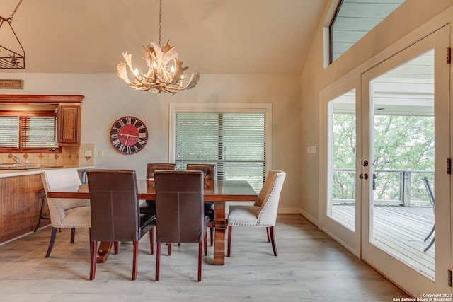 dining space featuring sink, a chandelier, light wood-type flooring, and vaulted ceiling