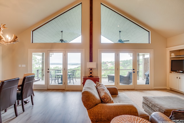 living room featuring plenty of natural light, high vaulted ceiling, light hardwood / wood-style floors, and ceiling fan with notable chandelier