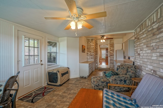 living room featuring tile patterned floors, ceiling fan, and brick wall