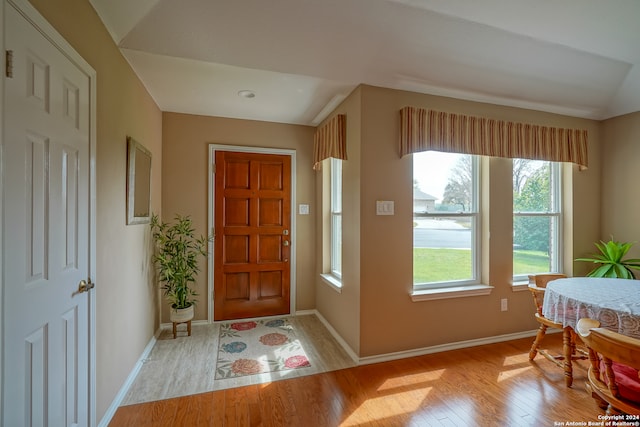 foyer with light wood-type flooring and vaulted ceiling