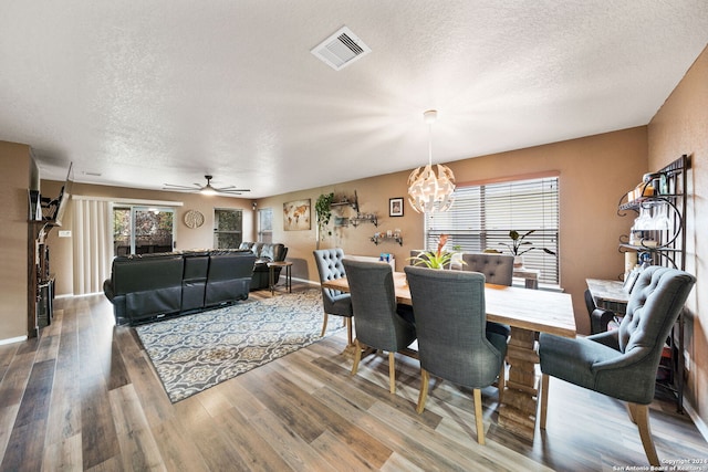 dining room featuring a textured ceiling, ceiling fan with notable chandelier, and hardwood / wood-style flooring