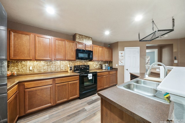 kitchen featuring backsplash, light hardwood / wood-style floors, black appliances, and sink