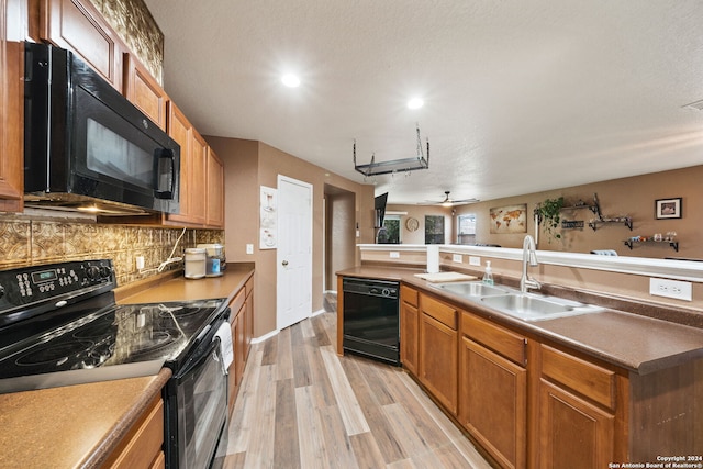 kitchen with tasteful backsplash, light wood-type flooring, black appliances, ceiling fan, and sink