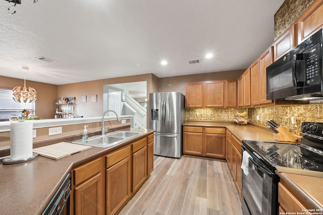 kitchen with decorative light fixtures, black appliances, an inviting chandelier, sink, and light hardwood / wood-style flooring