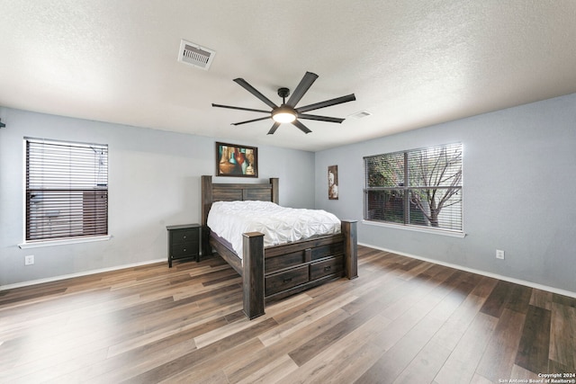 bedroom featuring a textured ceiling, dark hardwood / wood-style floors, and ceiling fan