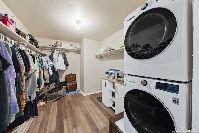 washroom with stacked washer / dryer, a textured ceiling, and light hardwood / wood-style flooring