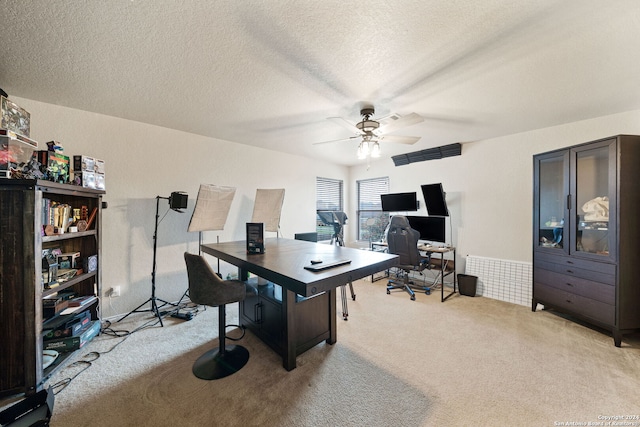 carpeted office space with a textured ceiling and ceiling fan