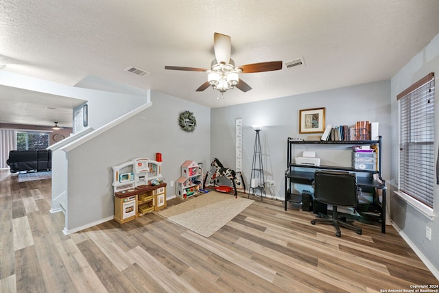 office with light hardwood / wood-style flooring, ceiling fan, and a textured ceiling