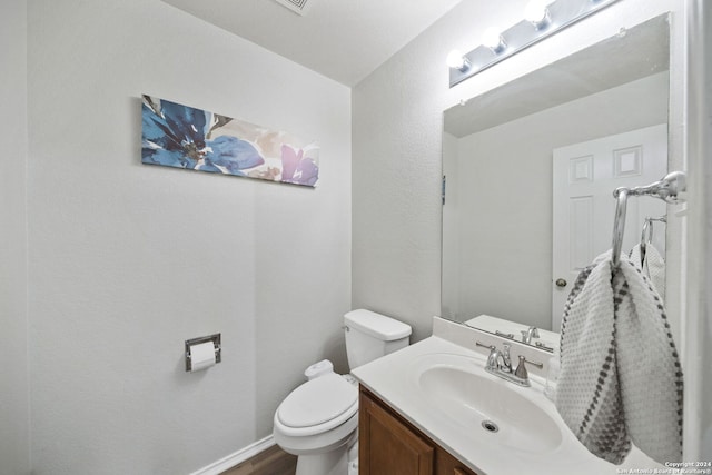 bathroom with toilet, vanity, and wood-type flooring