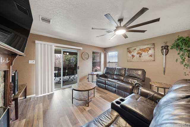 living room featuring ceiling fan, a textured ceiling, and light hardwood / wood-style floors