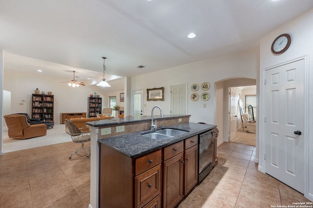 kitchen featuring sink, pendant lighting, dark stone countertops, dishwasher, and an island with sink