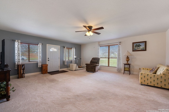 carpeted living room featuring ceiling fan and a textured ceiling