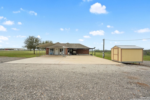 view of front facade with a carport, a storage unit, and a front lawn