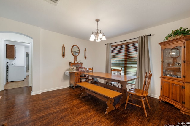 dining space with dark hardwood / wood-style flooring, washer / dryer, and an inviting chandelier