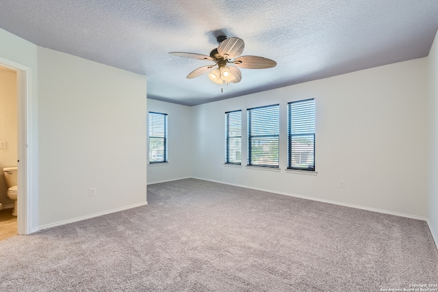 spare room with ceiling fan, light carpet, and a textured ceiling