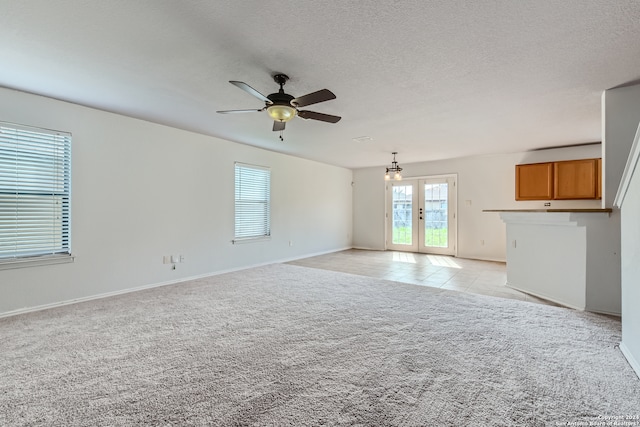 empty room featuring french doors, a textured ceiling, light colored carpet, and ceiling fan