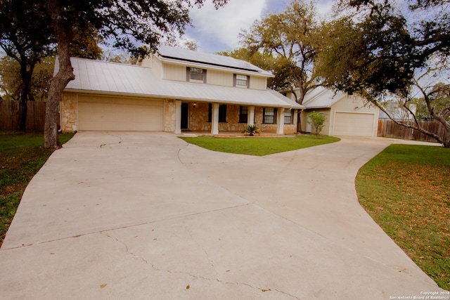 view of front of home featuring covered porch, solar panels, a garage, and a front yard