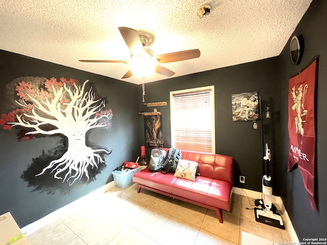 recreation room with ceiling fan, light tile flooring, and a textured ceiling