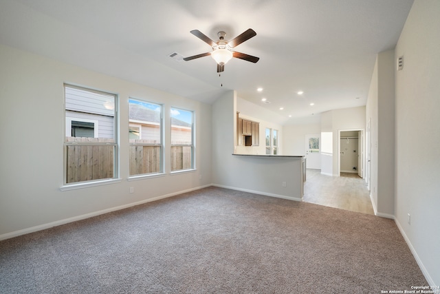 unfurnished living room with ceiling fan, lofted ceiling, and light carpet