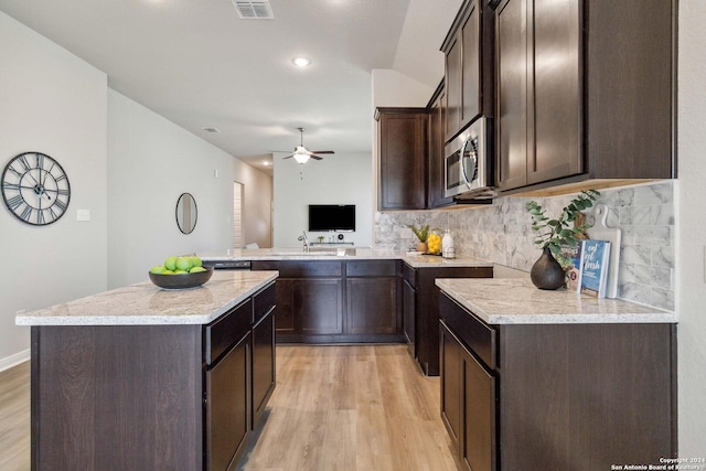 kitchen with sink, light hardwood / wood-style flooring, kitchen peninsula, decorative backsplash, and dark brown cabinets