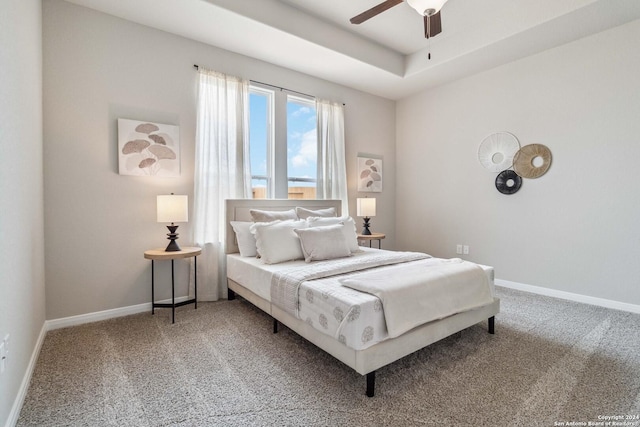 bedroom featuring carpet floors, a tray ceiling, and ceiling fan