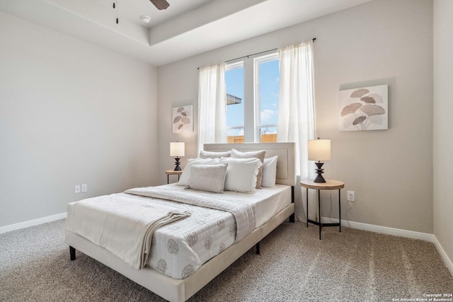 carpeted bedroom featuring a raised ceiling and ceiling fan