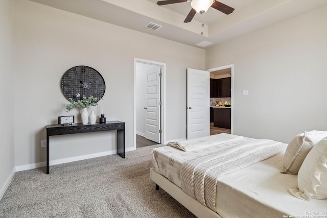 bedroom with a raised ceiling, ceiling fan, and carpet flooring